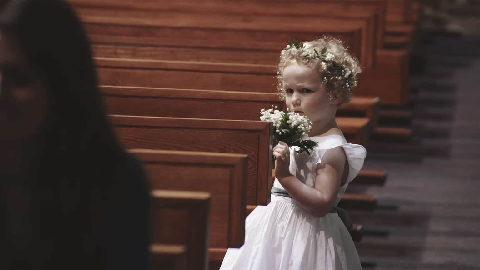 Flower girl looking ab sad and holding flowers