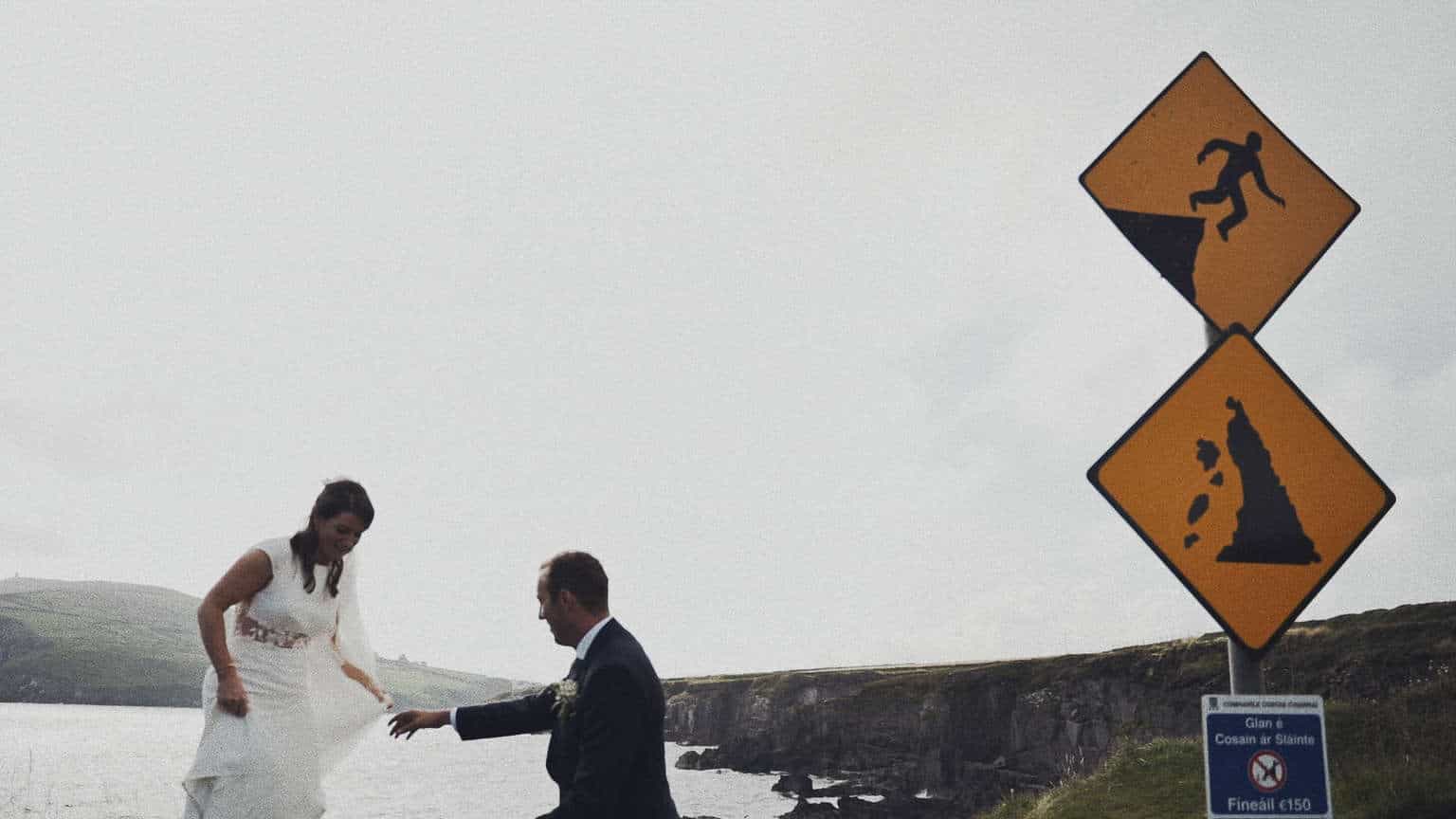 Bride and groom coming down from danger cliffs during wedding photo .
