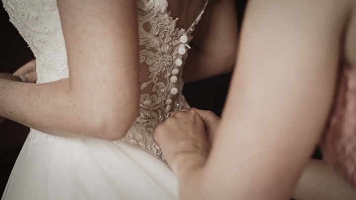 Bridesmaid tiding buttons at back of wedding dress