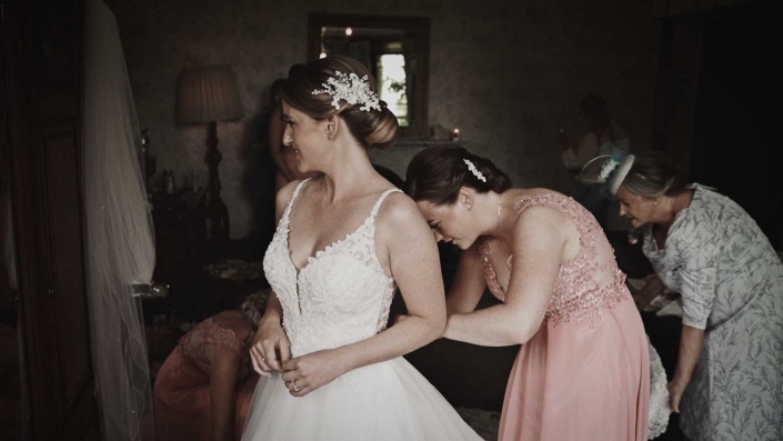Bridsmaid with mom are helping Jayne to dress wedding dress
