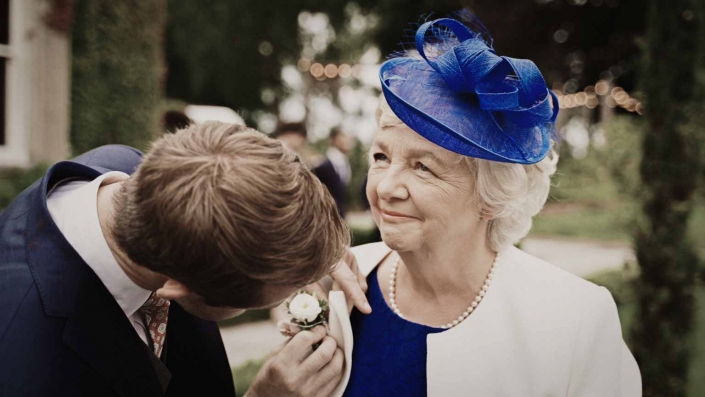 Groom attaching flower to Mom shoulder