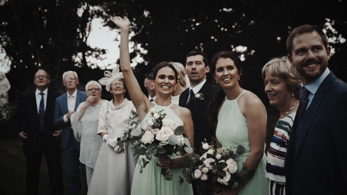 bridesmaid holding bouquet and waving to take picture