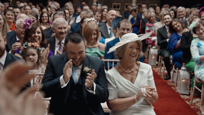 Mother clapping to wedding kiss.