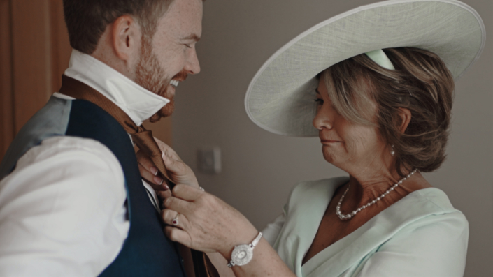 Mother is ties up tie for soon before ceremony.